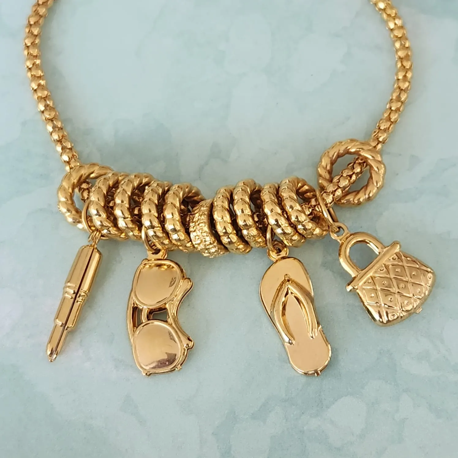 PULSEIRA DOURADA PINGENTES BATOM,ÓCULOS,CHINELO E BOLSA