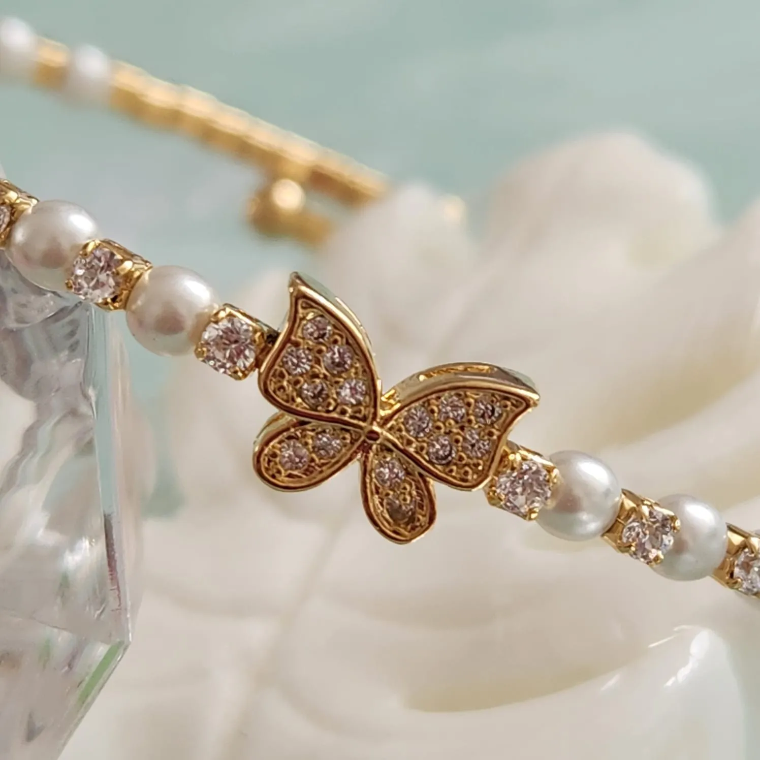 BRACELETE CRAVEJADO EM MICROZIRCÔNIAS CRISTAIS E PÉROLAS DETALHE BORBOLETA