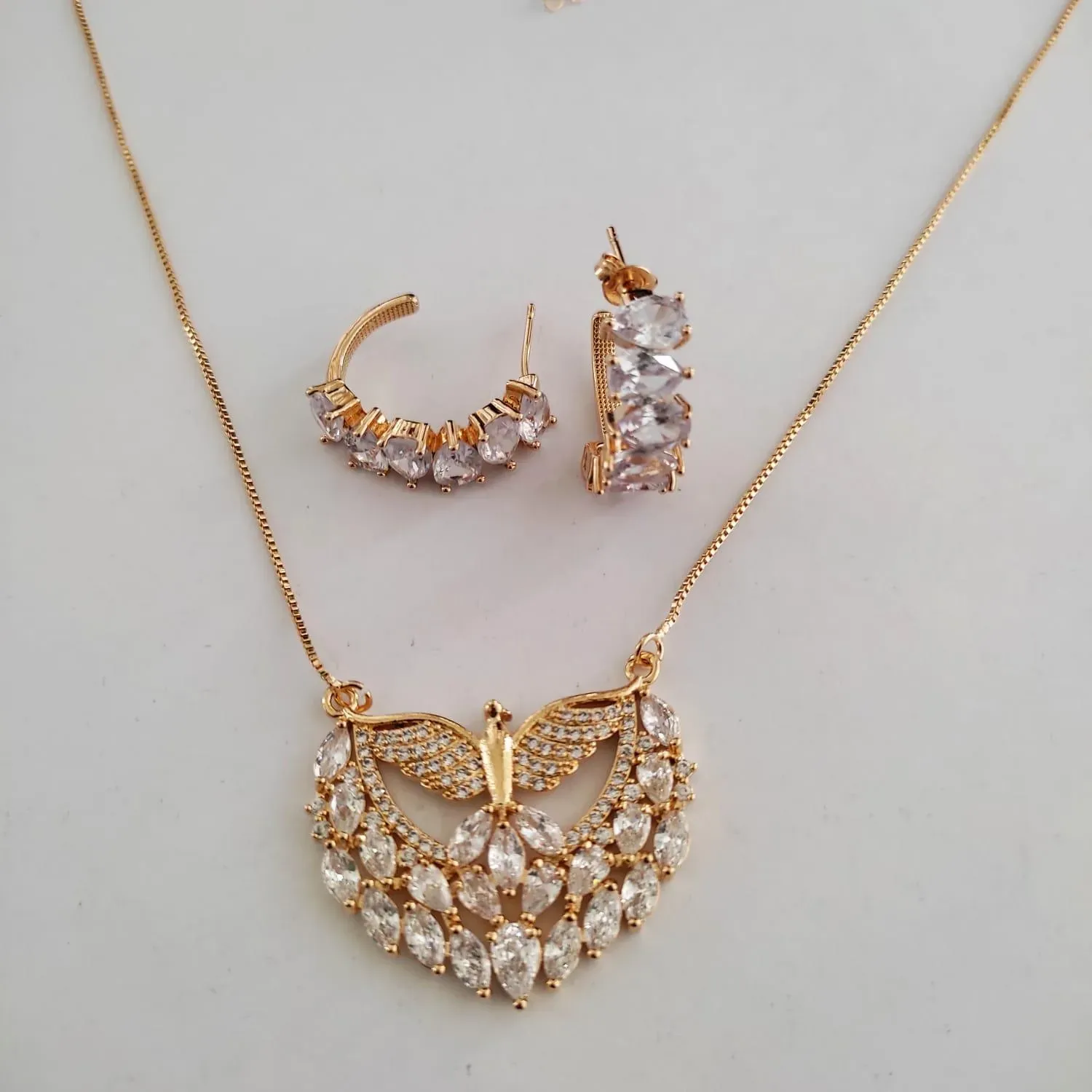 CONJUNTO DOURADO DIVINO ESPÍRITO SANTO CRAVEJADO EM MICROZIRCÔNIAS CRISTAL E ZIRCÔNIAS NAVETE CRISTAL E ARGOLA ZIRCÔNIAS NAVETE CRISTAL
