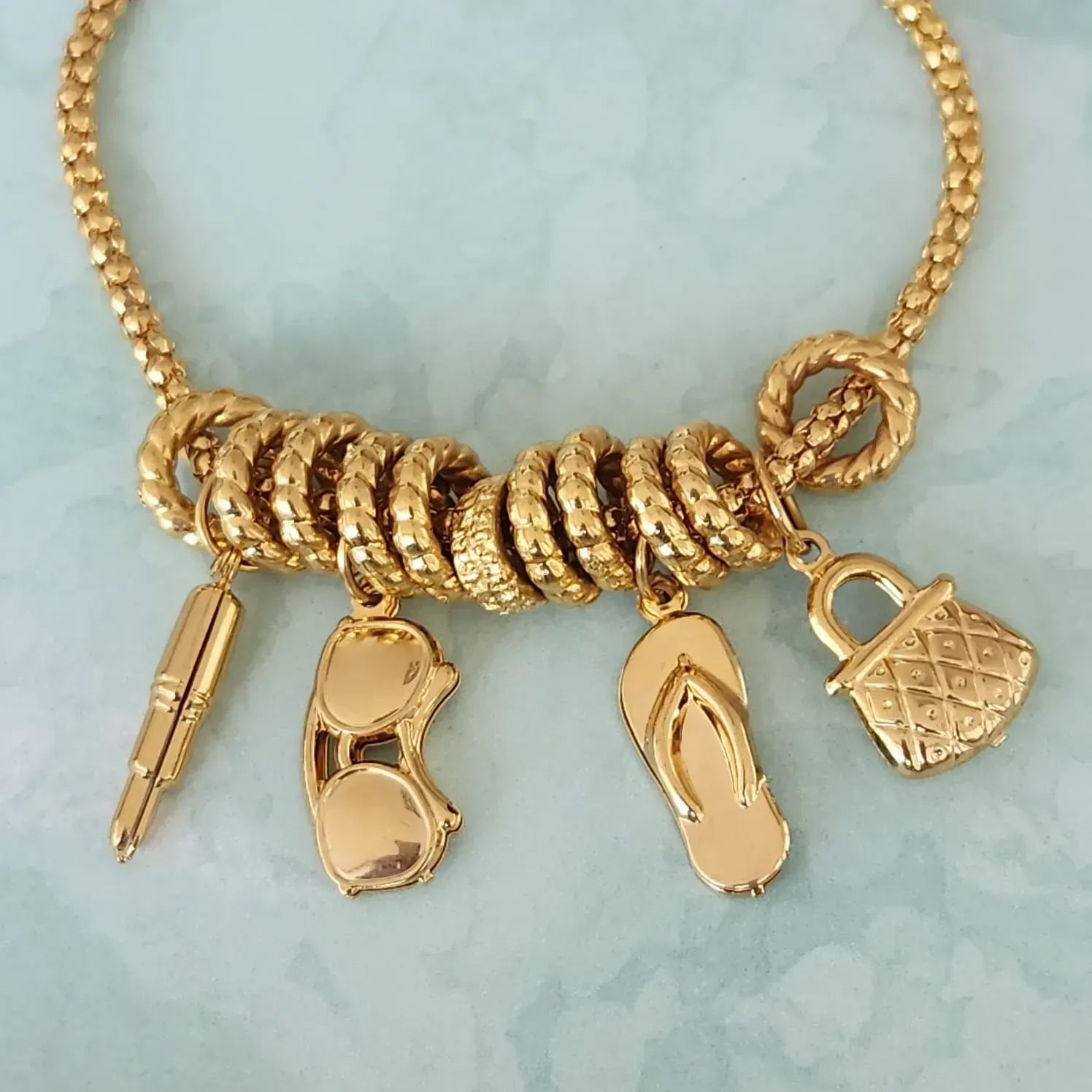 PULSEIRA DOURADA PINGENTES BATOM,ÓCULOS,CHINELO E BOLSA