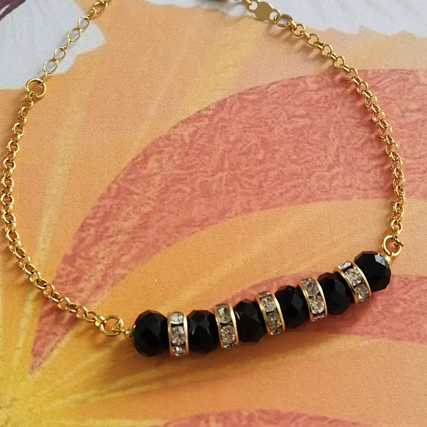 PULSEIRA DOURADA PEDRAS NEGRAS E CRISTAL