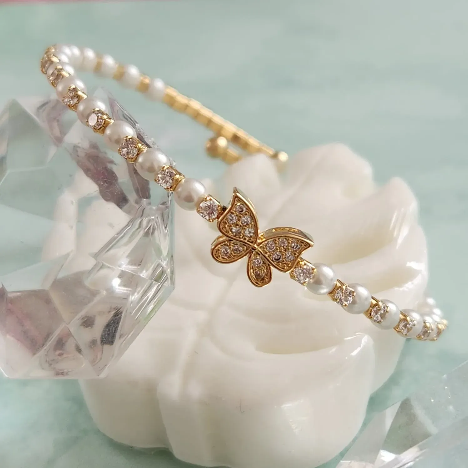 BRACELETE CRAVEJADO EM MICROZIRCÔNIAS CRISTAIS E PÉROLAS DETALHE BORBOLETA